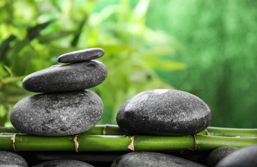 Zen stones on bamboo against blurred background