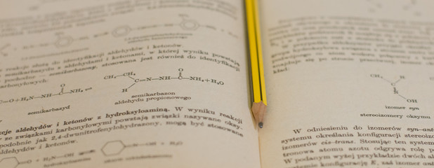 żółty ołówek na tle książki do chemii