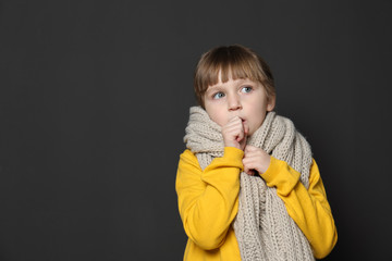 Cute little girl coughing against dark background. Space for text