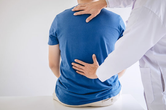 Doctor physiotherapist treating lower back pain patient after exercising