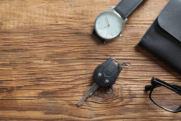 Flat lay composition with male accessories and car key on wooden background. Space for text