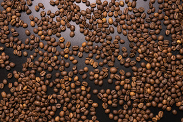 Roasted coffee beans in bulk on a black background