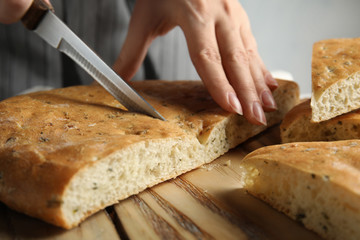 Woman cutting bread on wooden board, closeup