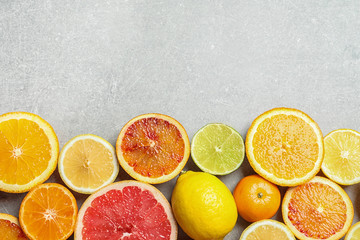 Different citrus fruits on grey background, flat lay. Space for text