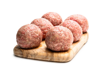 Raw meat balls on wooden cutting board isolated on white