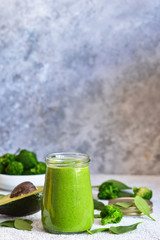Green smoothie with spinach, avocado and broccoli on a concrete background.