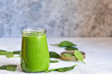 Fresh, green smoothie with spinach on a concrete background.