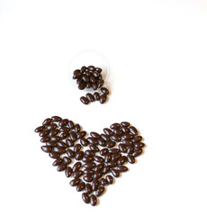 Nuts arranged in heart shape on background. Food image close up candy, chocolate milk, extra dark almond nuts. Love Texture on white grey table top view background on the cup plate