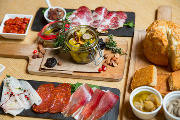 Cutting board with prosciutto, salami,bread on dark stone background.