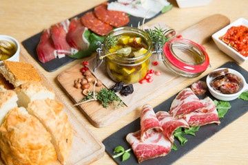 Cutting board with prosciutto, salami,bread on dark stone background.