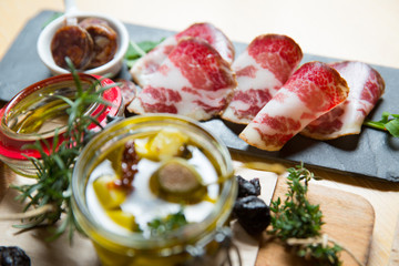 Cutting board with prosciutto, salami,bread on dark stone background.