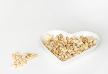 Nuts arranged in heart  on background. Healthy Food image close up cashew nuts. Love Texture on white grey table top view background on the cup plate