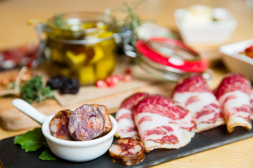Cutting board with prosciutto, salami,bread on dark stone background.