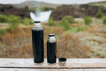 black thermos for tea standing in the nature.