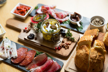 Cutting board with prosciutto, salami,bread on dark stone background.