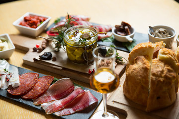 Cutting board with prosciutto, salami,bread on dark stone background.