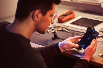 The technician carefully examines the integrity of the internal elements of the smartphone in a modern repair shop