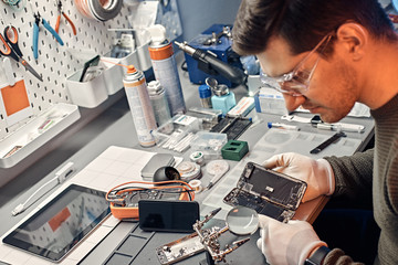 Fototapeta na wymiar The technician carefully examines the integrity of the internal elements of the smartphone in a modern repair shop