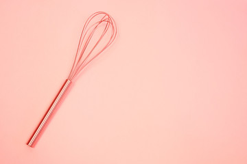 whisk on  pink pastel background. Top view, minimalism. toned Living coral