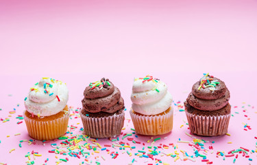 Cupcakes with colorful sprinkles on pink background, copy space.