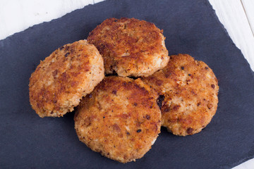 cutlets on a black flat plate, on a white wooden background