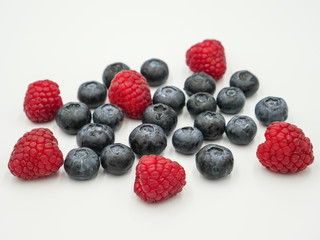 Blueberries and raspberries on white background