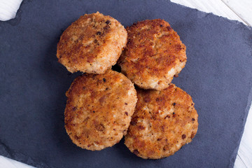 cutlets on a black flat plate, on a white wooden background