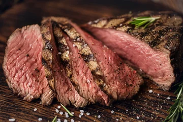  Sappige medium Beef Rib Eye steak plakjes op een houten bord met kruiden, specerijen en zout. © nata_zhekova