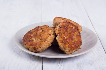 cutlets on a grey plate, on a white wooden background