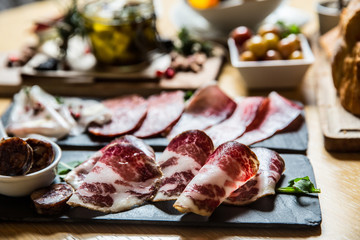 Cutting board with prosciutto, salami,bread on dark stone background.