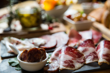 Cutting board with prosciutto, salami,bread on dark stone background.