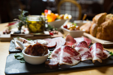Cutting board with prosciutto, salami,bread on dark stone background.
