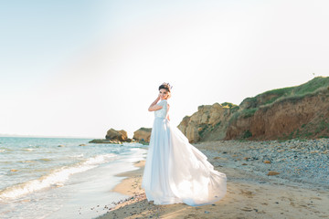 Fototapeta na wymiar Beautiful bride in luxury wedding dress with bouquet at the sea side. bride in a blue dress walk along the ocean shore. Wedding by the sea.
