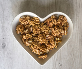Nuts arranged in heart  on background. Healthy Food image close up walnuts nuts. Love Texture on white grey table top view background on the cup plate
