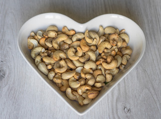 Nuts arranged in heart  on background. Healthy Food image close up cashew nuts. Love Texture on white grey table top view
