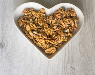 Nuts arranged in heart  on background. Healthy Food image close up walnuts nuts. Love Texture on white grey table top view background on the cup plate