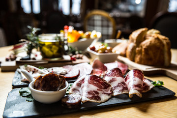 Cutting board with prosciutto, salami,bread on dark stone background.