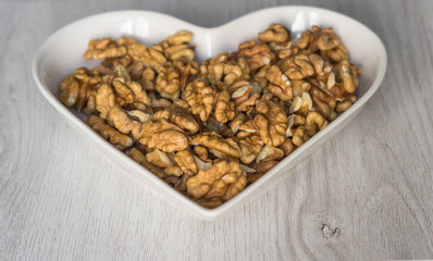 Nuts arranged in heart  on background. Healthy Food image close up walnuts nuts. Love Texture on white grey table top view background on the cup plate