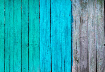 partially painted in shades of blue and turquoise fence of old wooden planks