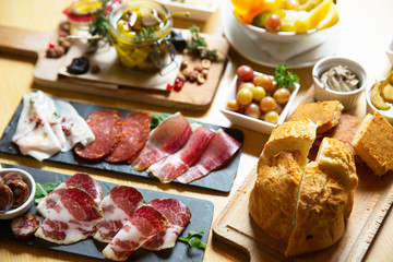Cutting board with prosciutto, salami,bread on dark stone background.