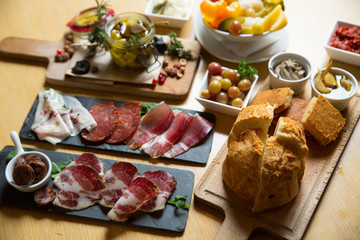 Cutting board with prosciutto, salami,bread on dark stone background.
