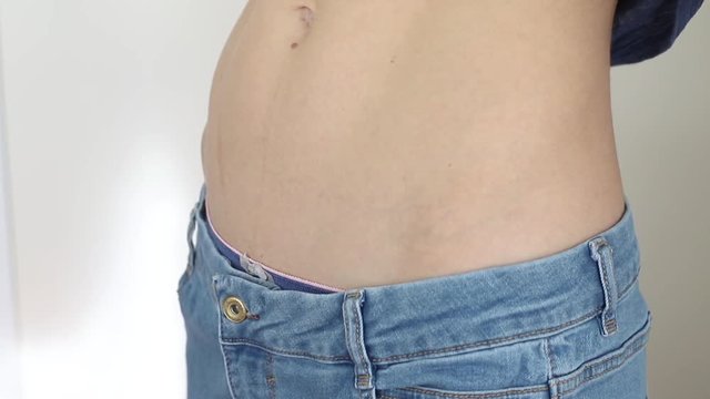 slim girl in too big jeans showing her belly