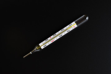 Mercury thermometer and pills on a black background.