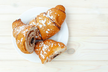 Fresh Croissant with chocolate on the white wooden background
