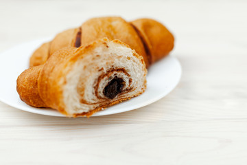Fresh Croissant with chocolate on the white wooden background