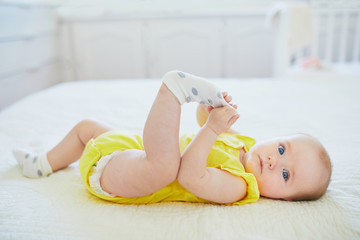 Adorable baby girl removing sock from her foot