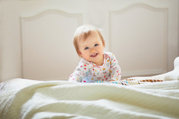 Fototapeta premium Baby girl crawling on bed and laughing