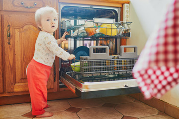 Little child helping to unload dishwasher