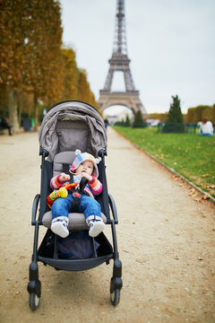 Adorable baby girl sitting in stroller near the Eiffel tower in Paris, France