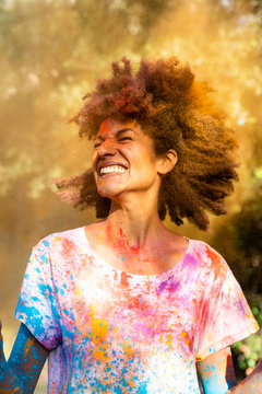 Woman shaking her head, full of colorful powder paint, celebrating Holi, Festival of Colors